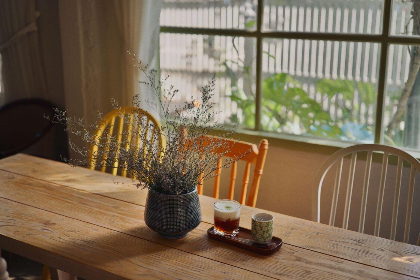 Mesa de madera de una cocina junto a la ventana, con luz de la tarde